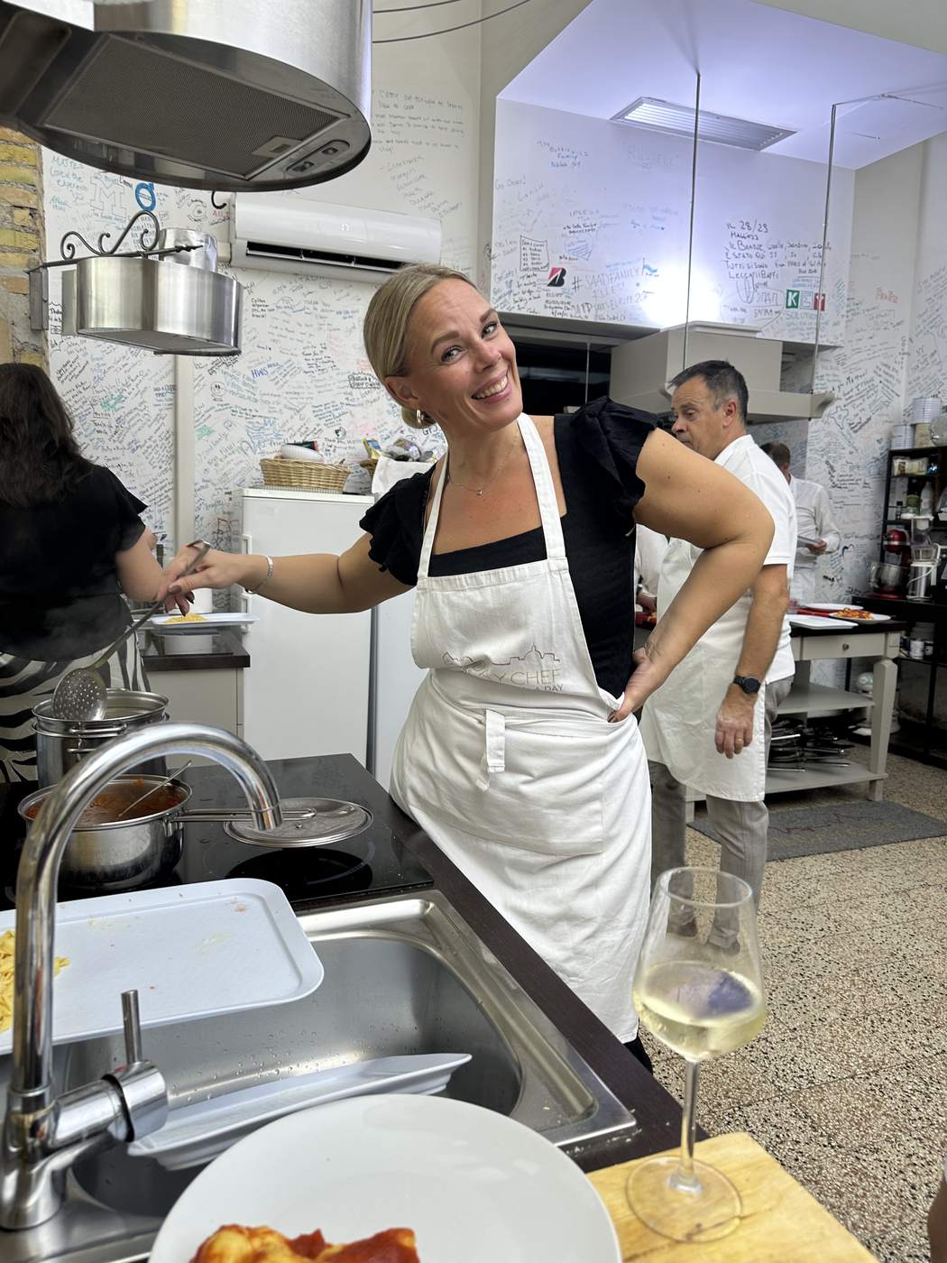 Partecipante sorridente con un calice di prosecco alla scuola di cucina One Day Chef a Roma
