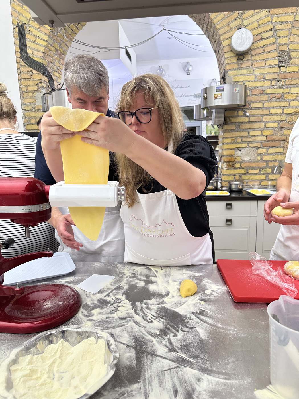 Due partecipanti che tirano la sfoglia insieme durante un corso di cucina per gruppi a Roma