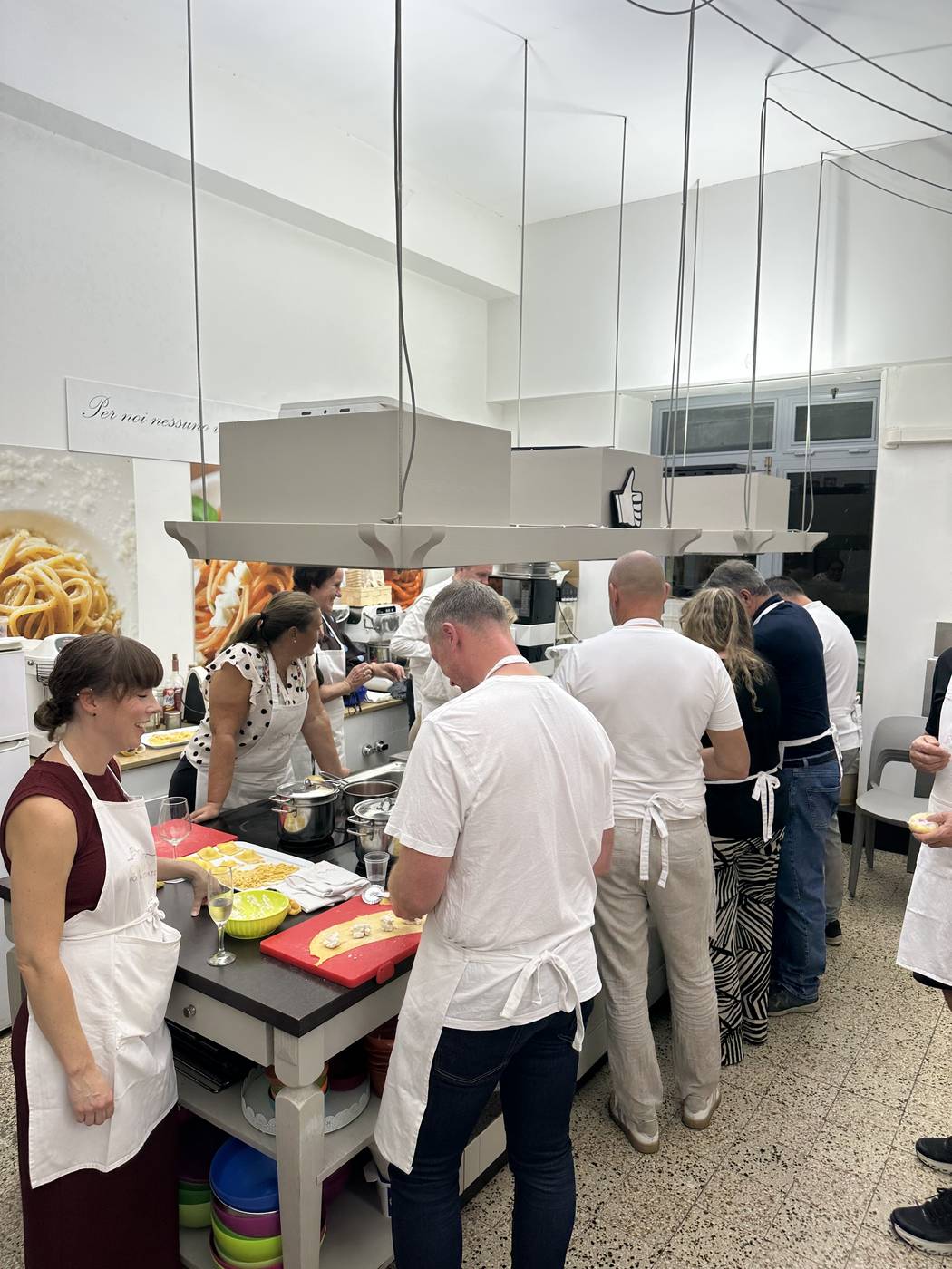 Gruppo di partecipanti che prepara la pasta fresca alle postazioni in una scuola di cucina a Roma